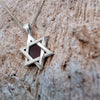 Close-up of 925 sterling silver Star of David pendant necklace featuring a central nanochip with the entire Hebrew Tanakh etched using nano-printing technology. Set against a textured stone background, this symbolic Jewish necklace embodies tradition, faith, and modern craftsmanship.