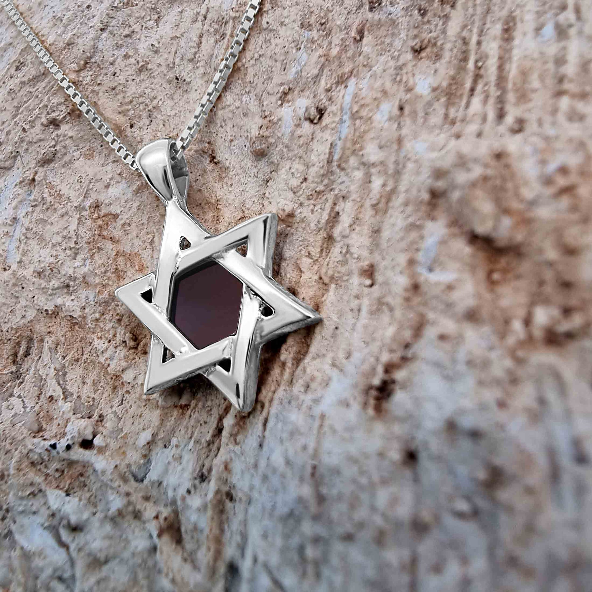 Close-up of 925 sterling silver Star of David pendant necklace featuring a central nanochip with the entire Hebrew Tanakh etched using nano-printing technology. Set against a textured stone background, this symbolic Jewish necklace embodies tradition, faith, and modern craftsmanship.