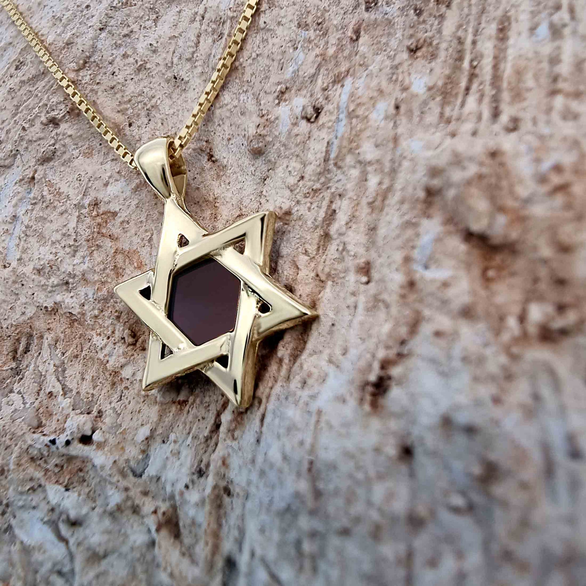 Close-up of gold-plated Star of David pendant necklace featuring a central nanochip with the entire Hebrew Tanakh etched using nano-printing technology. Set against a textured stone background, this symbolic Jewish necklace embodies tradition, faith, and modern craftsmanship.
