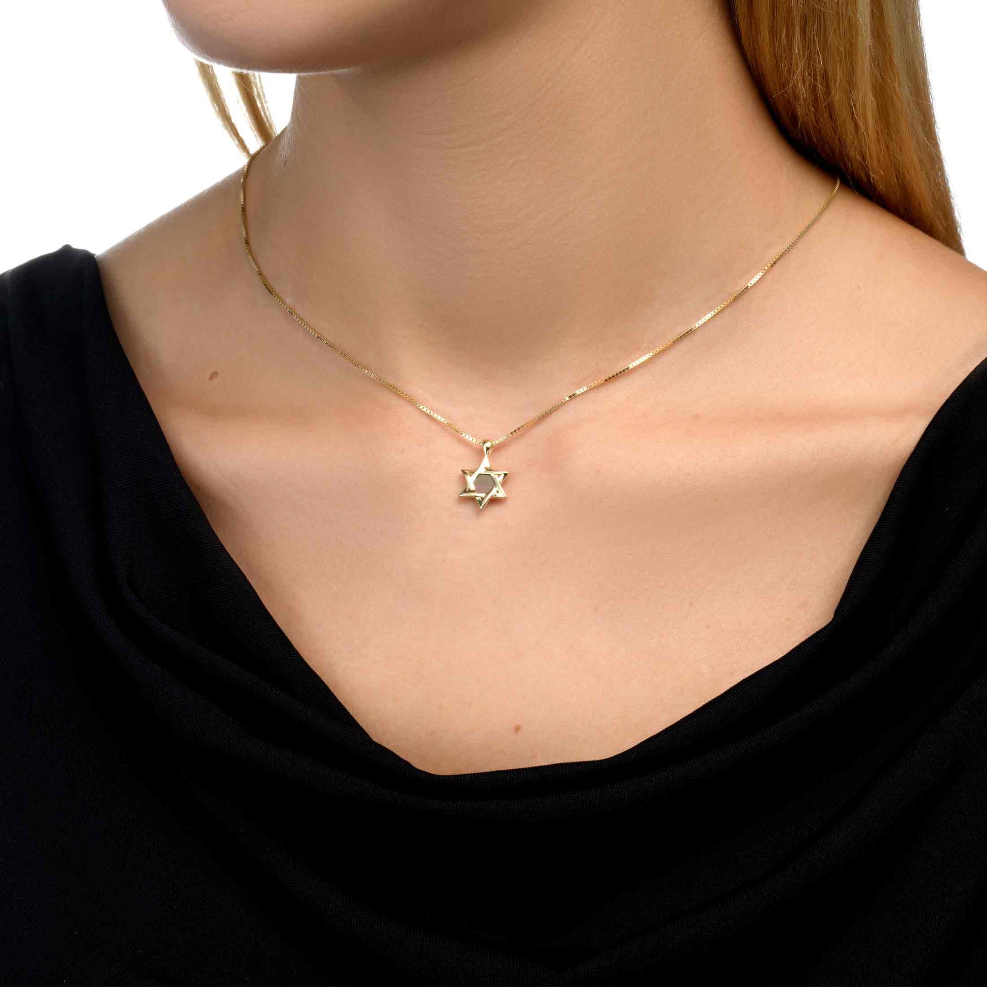 Model wearing the Eternal Heritage gold Star of David necklace with a subtle and refined presence on the neckline. The pendant holds a microchip inscribed with the entire Hebrew Bible, symbolizing faith and heritage with timeless elegance.