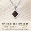 Silver Infinite Charm Nano Bible necklace laid over Hebrew scripture background. Features nano-printed full Tanakh. Unique spiritual and cultural gift for Jewish women.