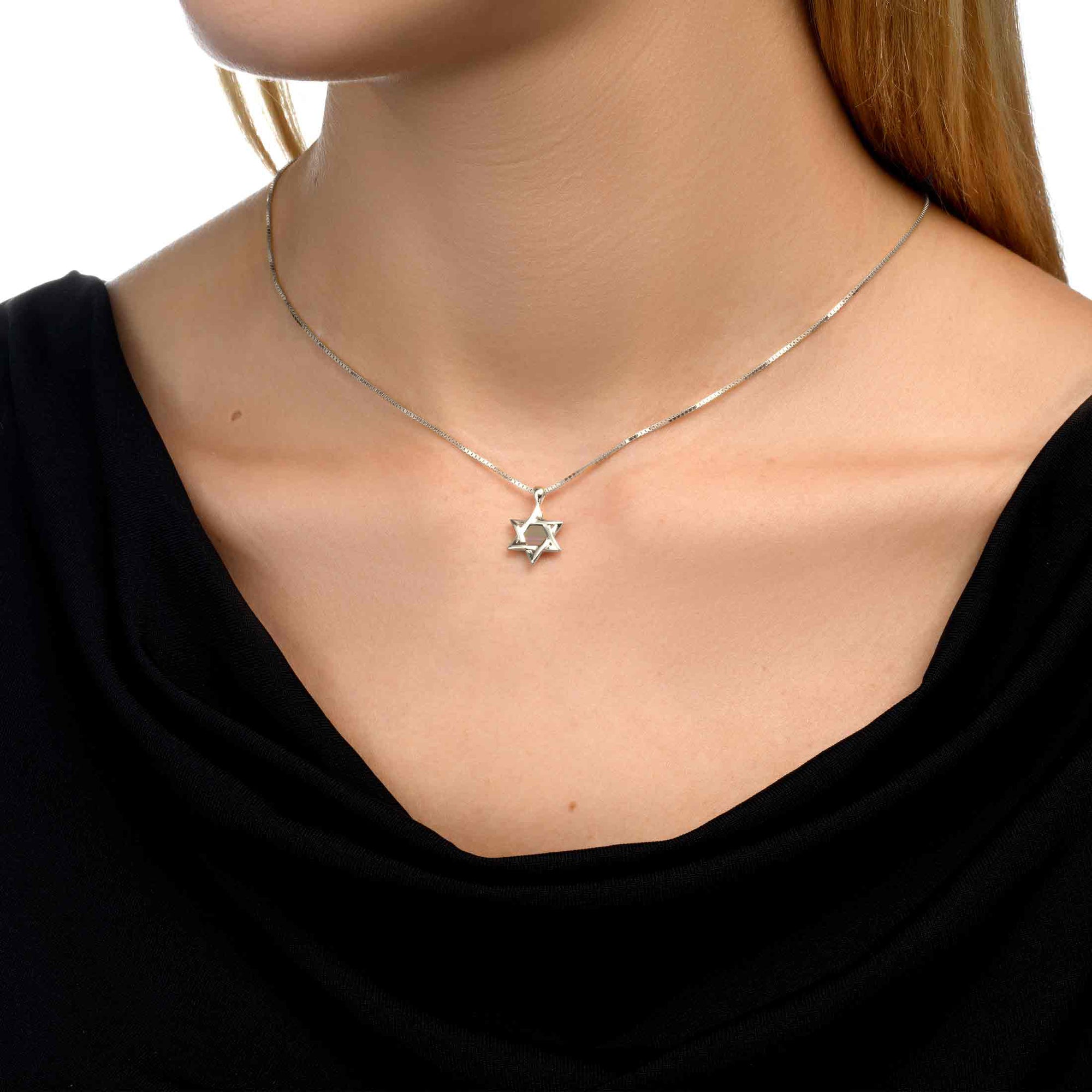 Model wearing the Eternal Heritage gold Star of David necklace with a subtle and refined presence on the neckline. The pendant holds a microchip inscribed with the entire Hebrew Bible, symbolizing faith and heritage with timeless elegance.